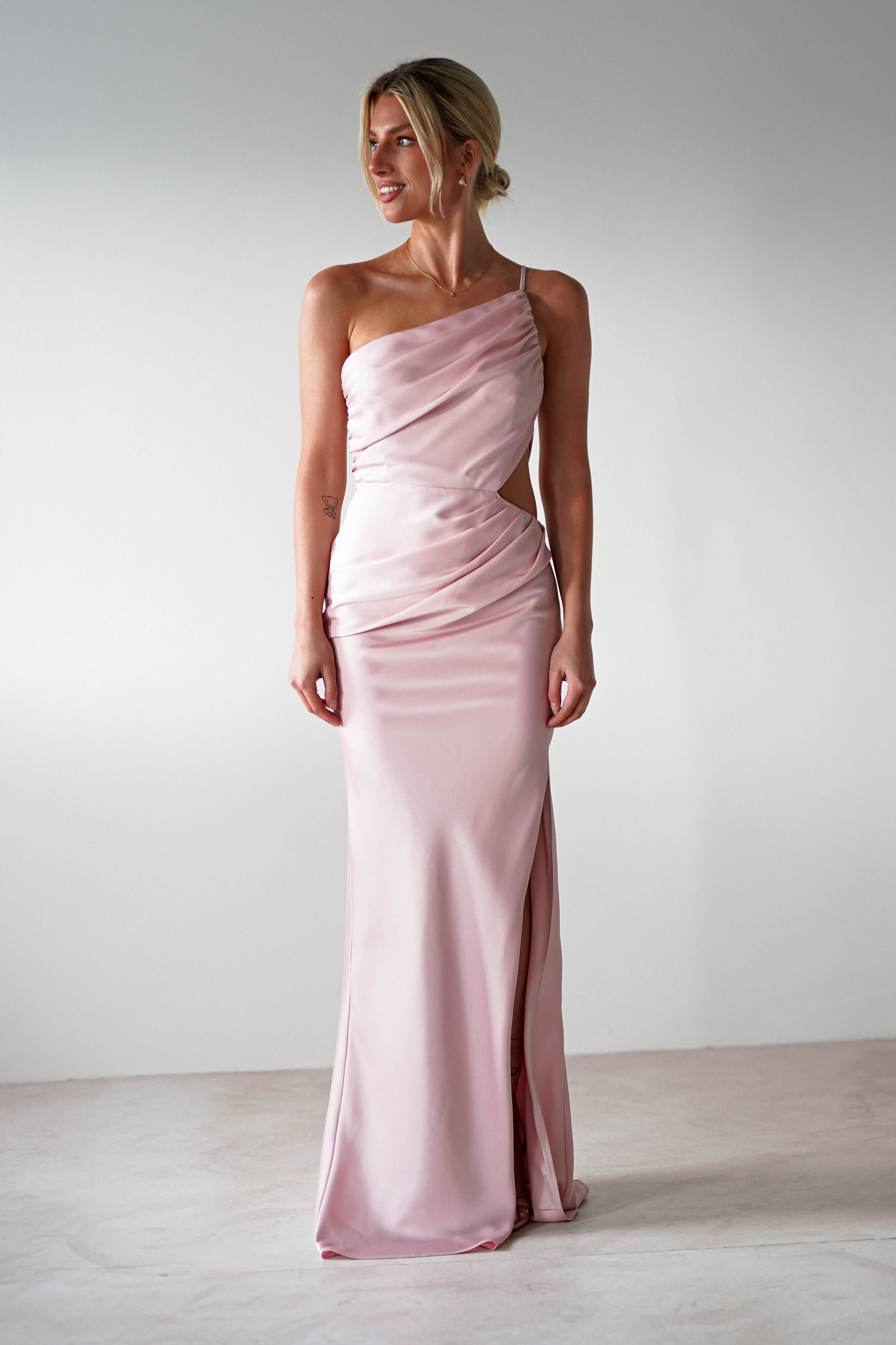 A woman in a pink satin maxi dress.