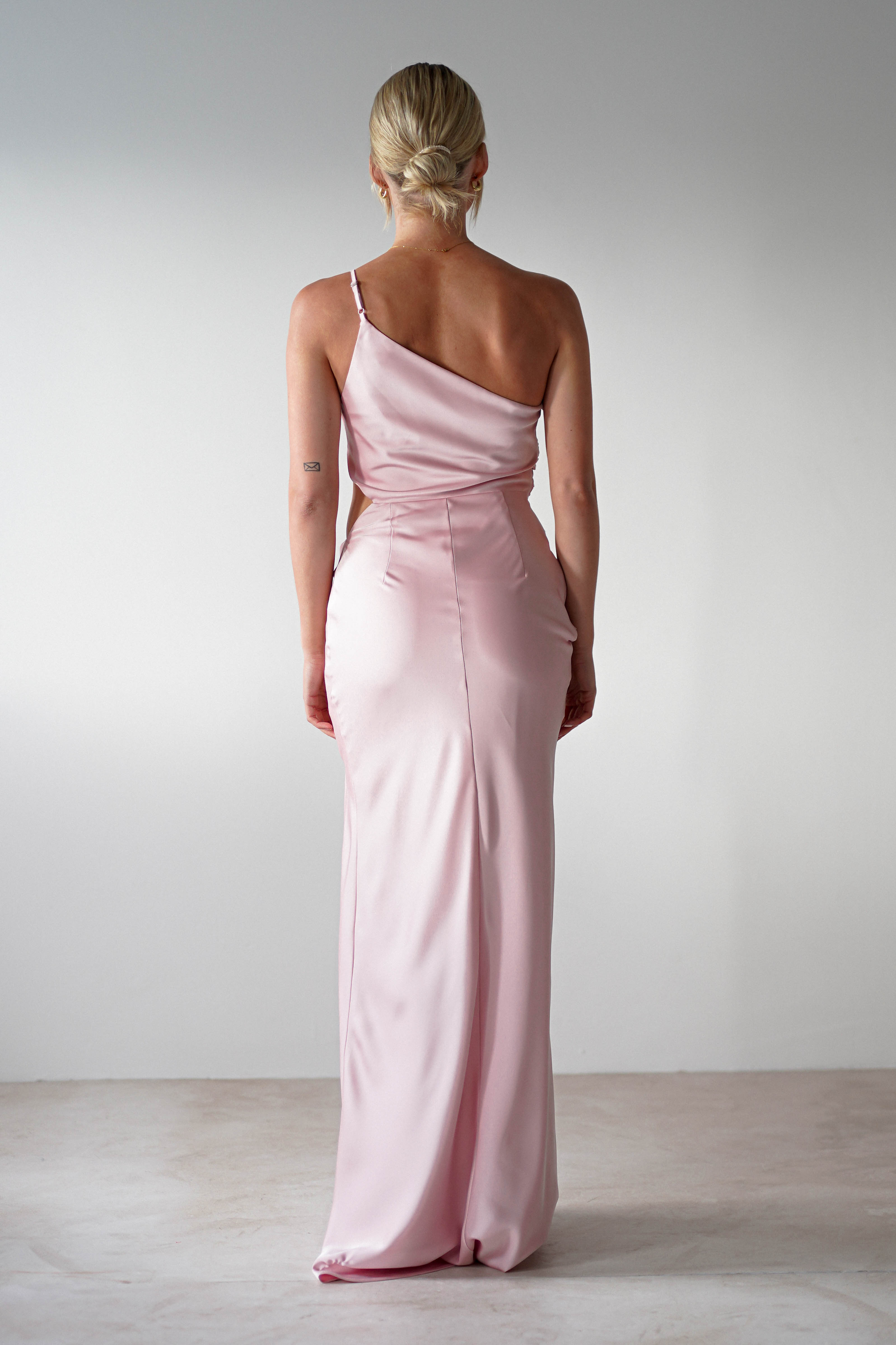 A woman in a pink satin maxi dress.