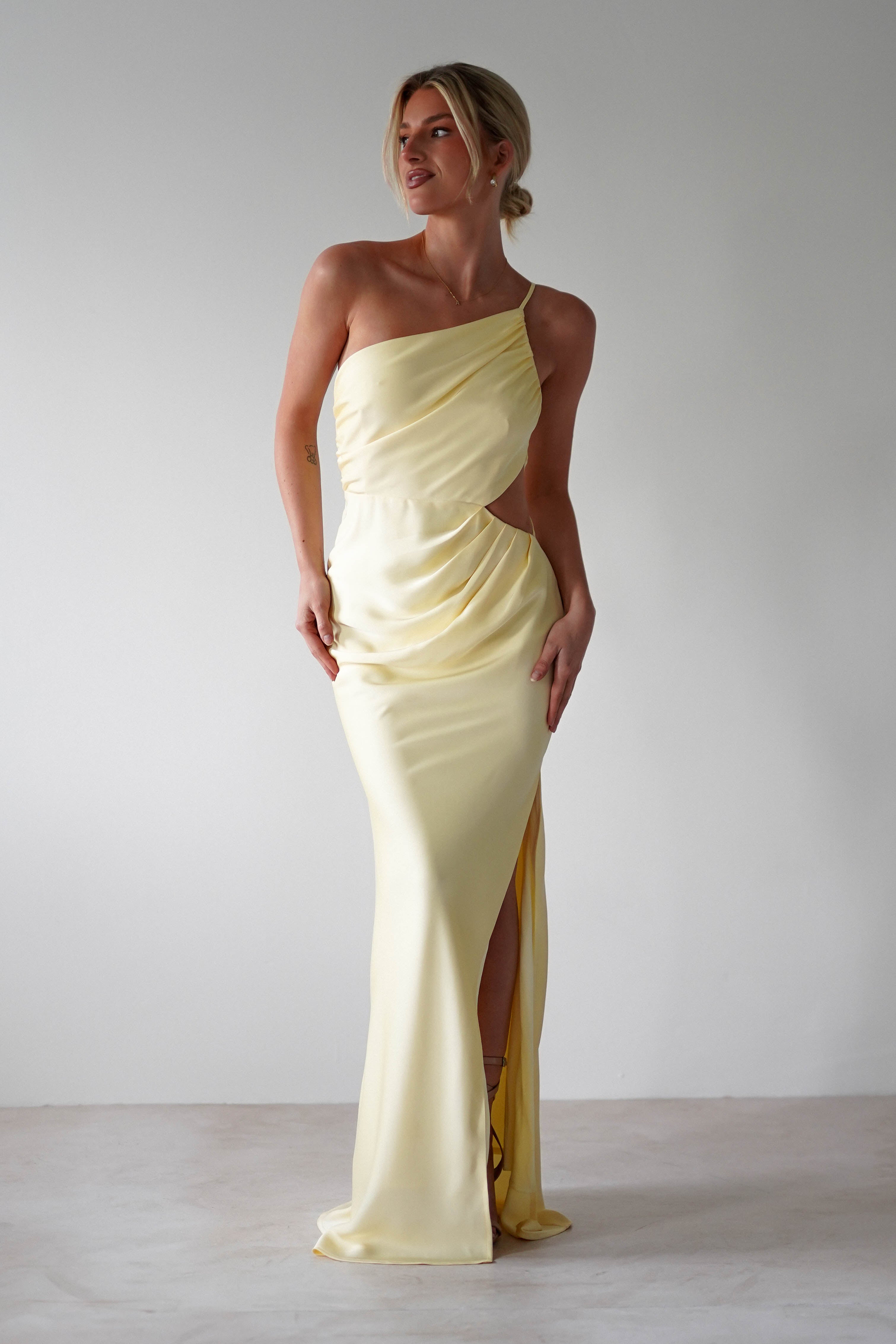 A woman in a matte satin yellow, one-shoulder satin maxi dress—perfect for bridesmaids.