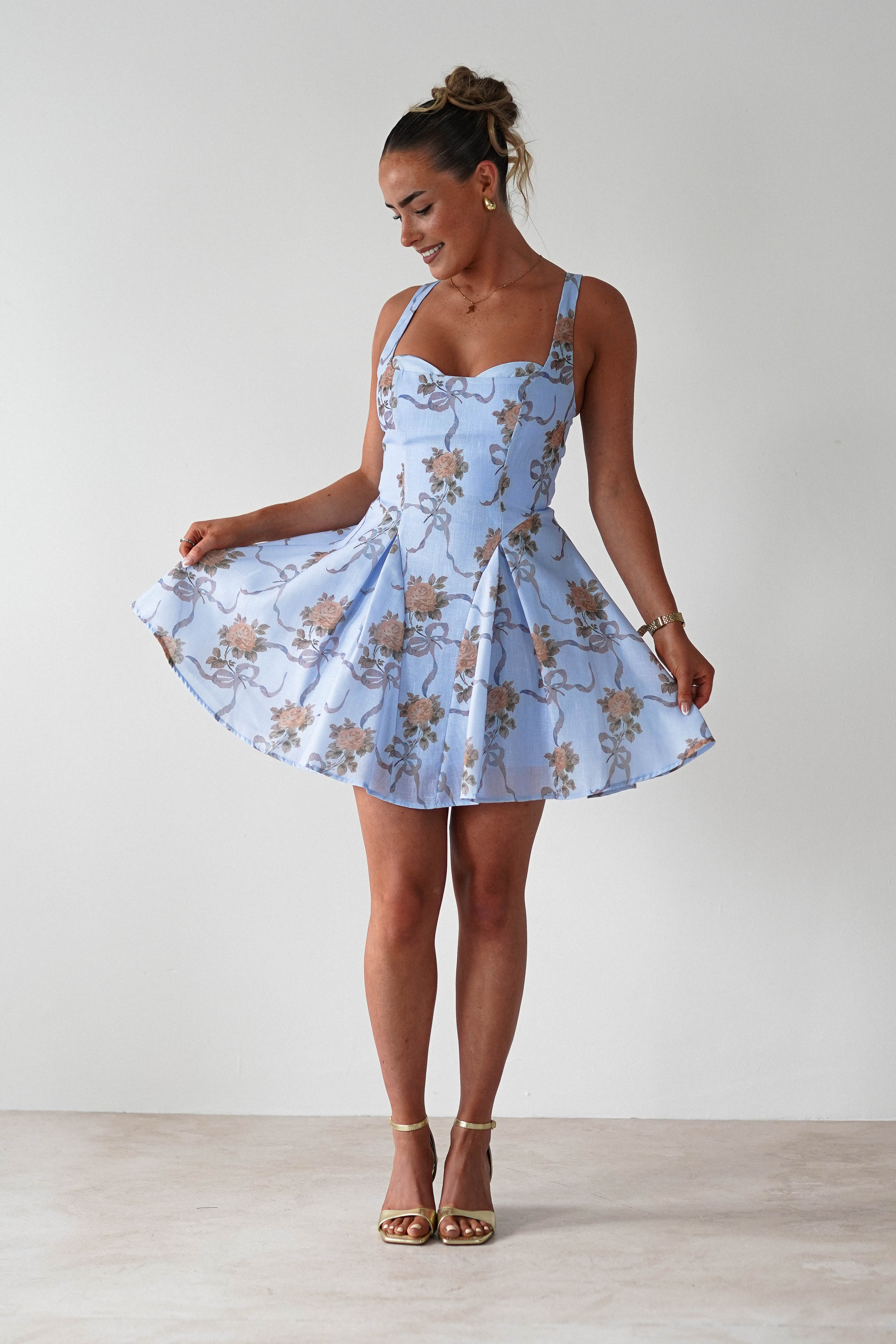 Woman wearing a light blue floral dress against a white background