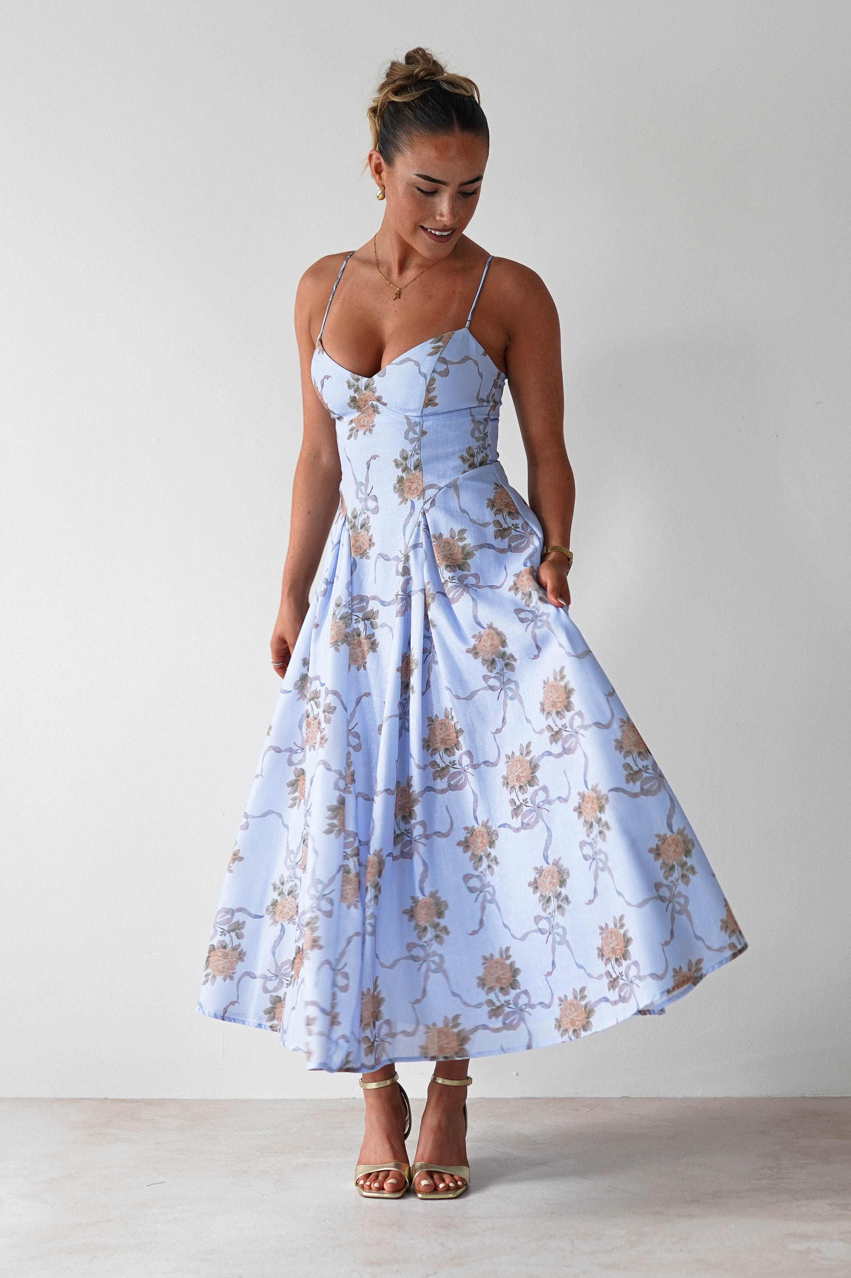 Woman wearing a light blue floral dress against a plain background