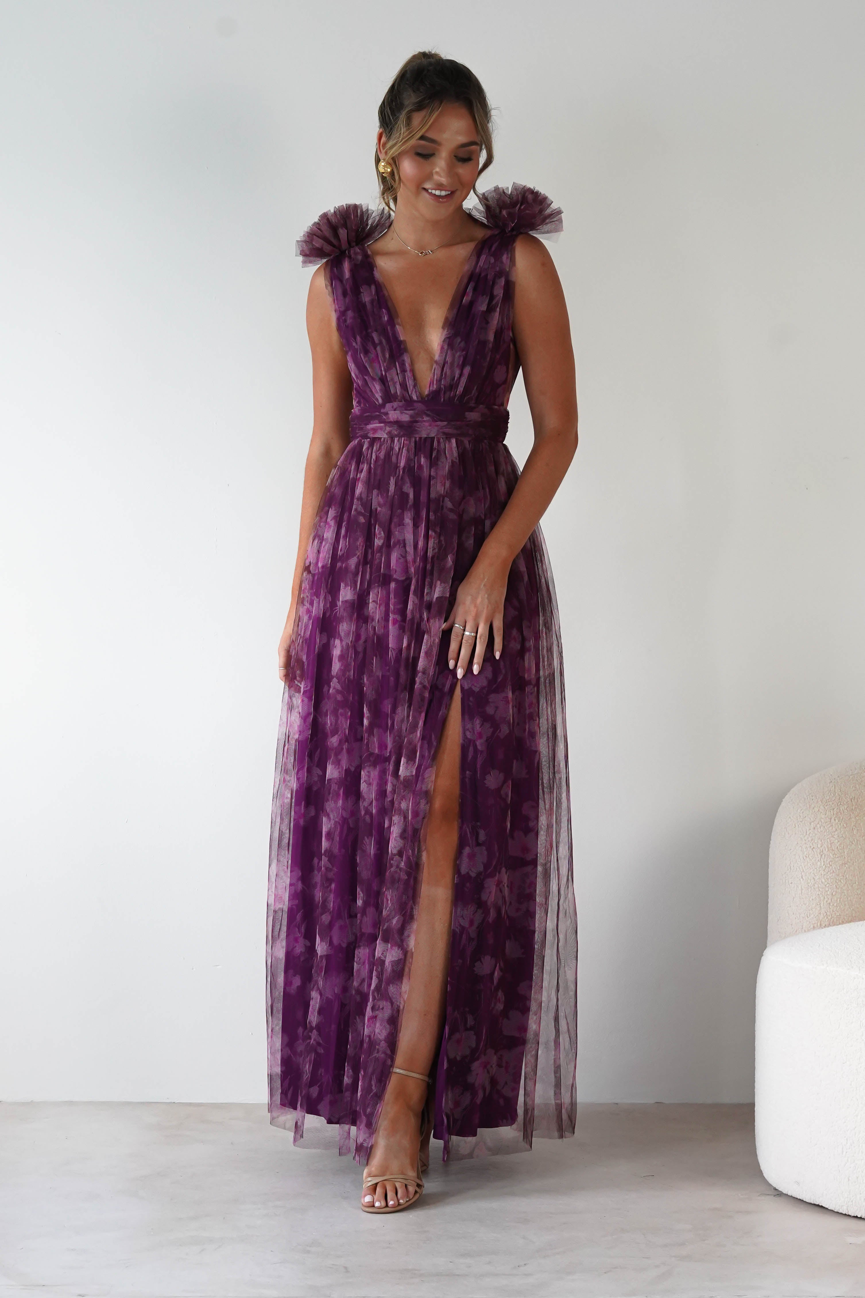 Woman wearing a purple dress with feathered shoulders against a white background