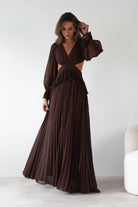 Woman wearing a brown dress with cut-out design against a white background