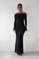 Woman wearing Katalina Sparkling Rhinestone Maxi Dress in black with off-shoulder neckline, long sleeves, and rhinestone embellishments throughout the fitted silhouette.