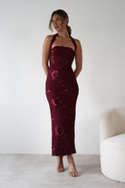 Woman wearing Lilani Textured Midaxi Dress in wine with halter neckline, embroidered floral detailing, and a body-hugging midaxi length, styled with nude heels.