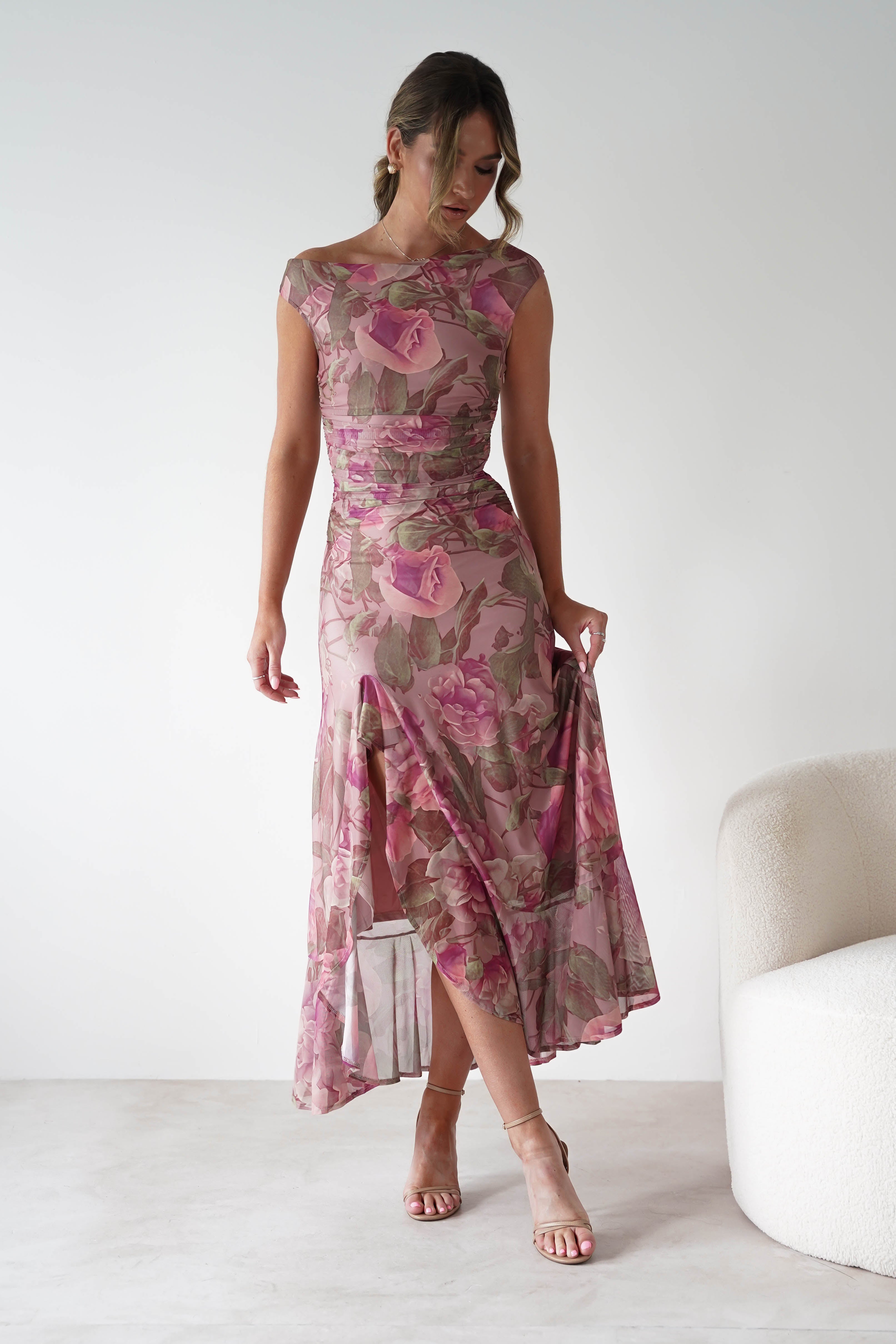 Woman wearing Milla Mesh Floral Bodycon Maxi Dress in blush with pink floral print, ruched detailing, and sheer mesh overlay, styled with nude strappy heels.