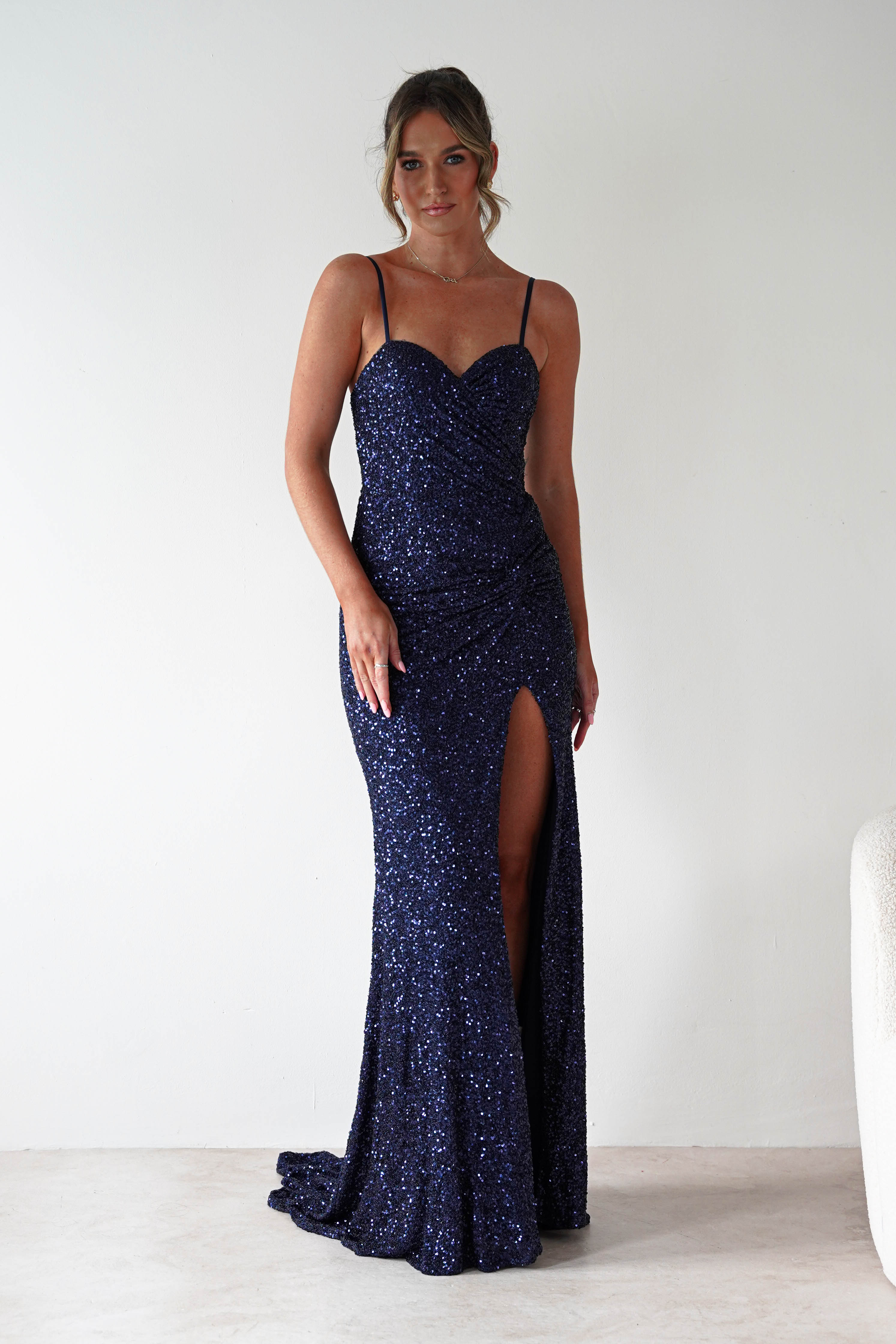 Woman wearing Nalita Bodycon Sequin Gown in navy with sweetheart neckline, sparkling sequin finish, bodycon fit, and thigh-high leg slit.